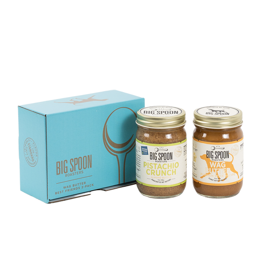 Two jars of Big Spoon Roasters nut butter in front of a closed blue gift box