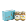 Two jars of Big Spoon Roasters nut butter in front of a closed blue gift box