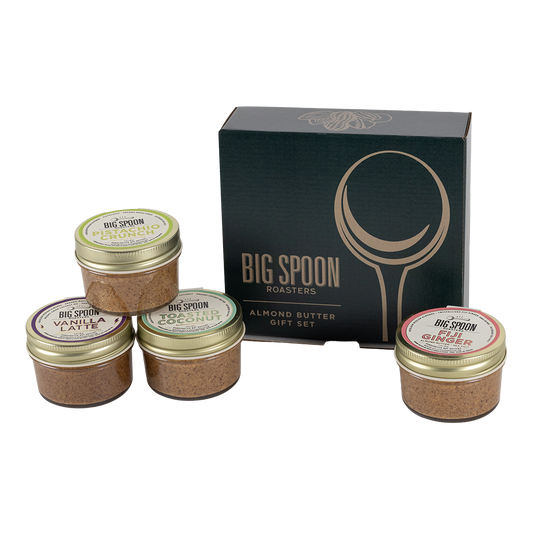 Set of four almond butter jars with 'Big Spoon Roasters' branding in front of a branded box on a white background