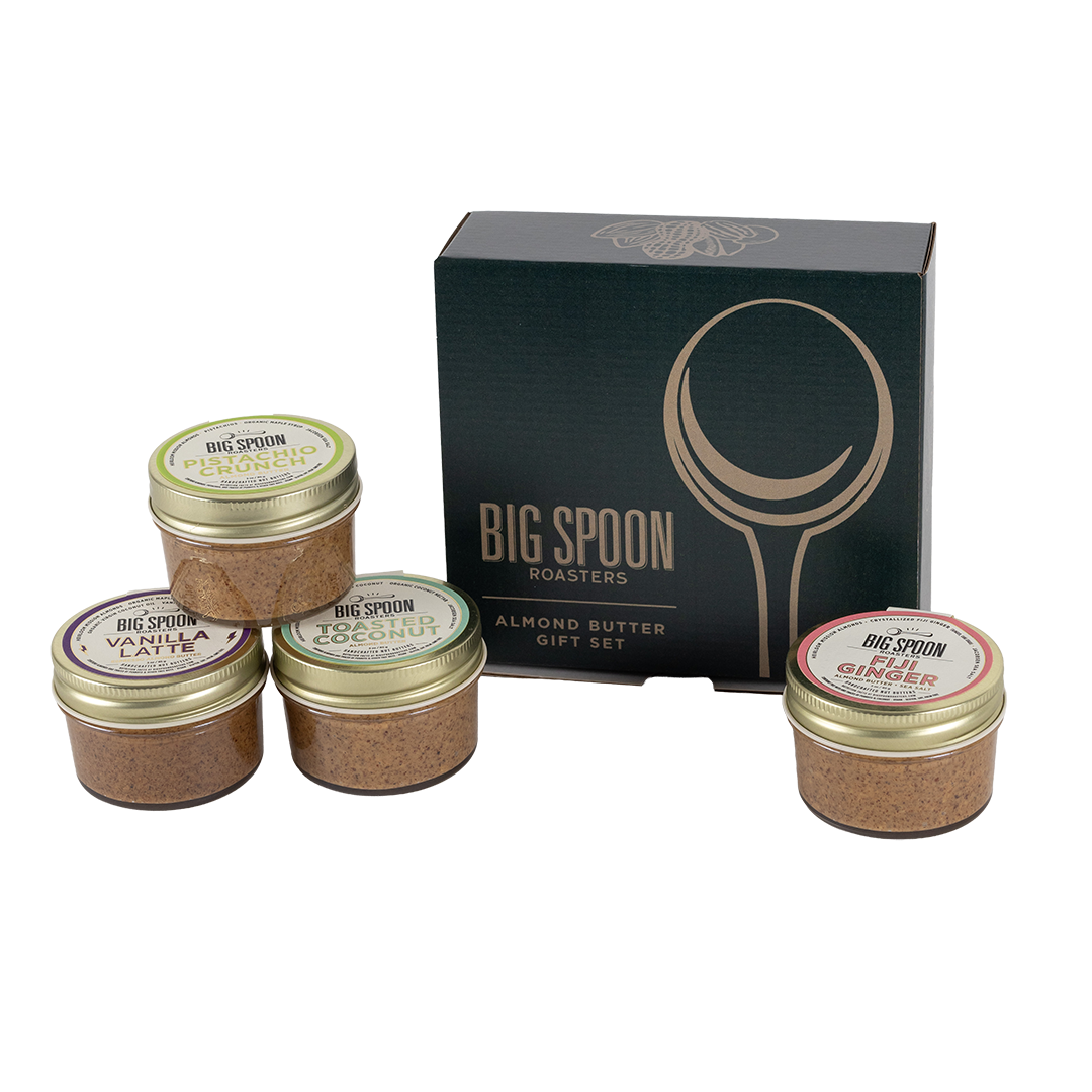 Set of four almond butter jars with 'Big Spoon Roasters' branding in front of a branded box on a white background