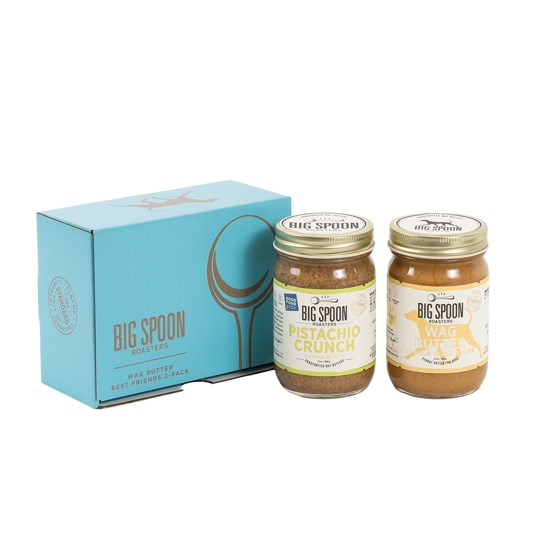 Two jars of Big Spoon Roasters nut butter in front of a closed blue gift box