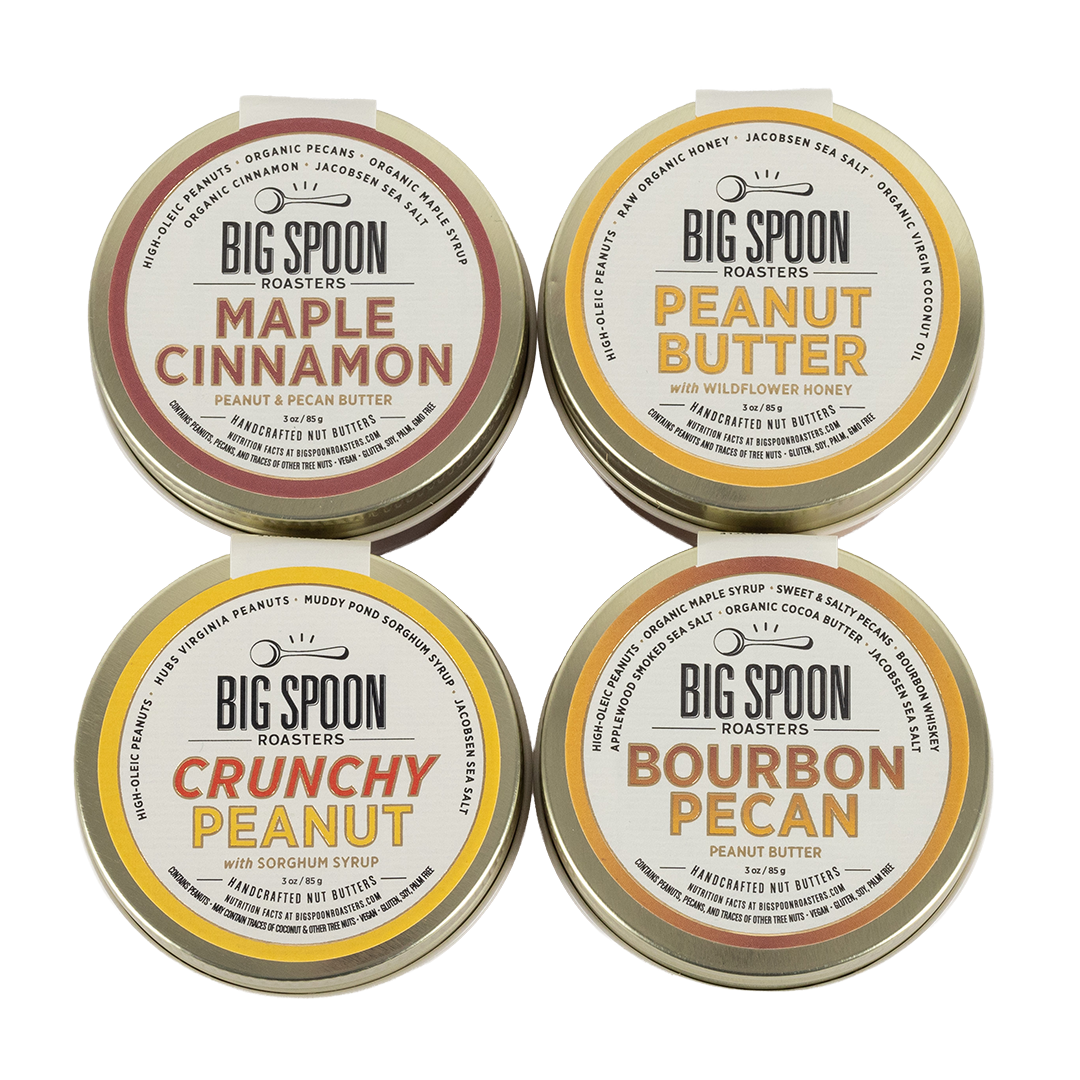 Four tins of Big Spoon Roasters peanut butter on a white background