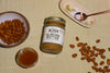 a jar of Almond Butter surrounded by a bowl of almonds, a jar of honey, sea salt, and other almonds