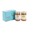 Two jars of Big Spoon Roasters nut butter in front of a closed blue gift box