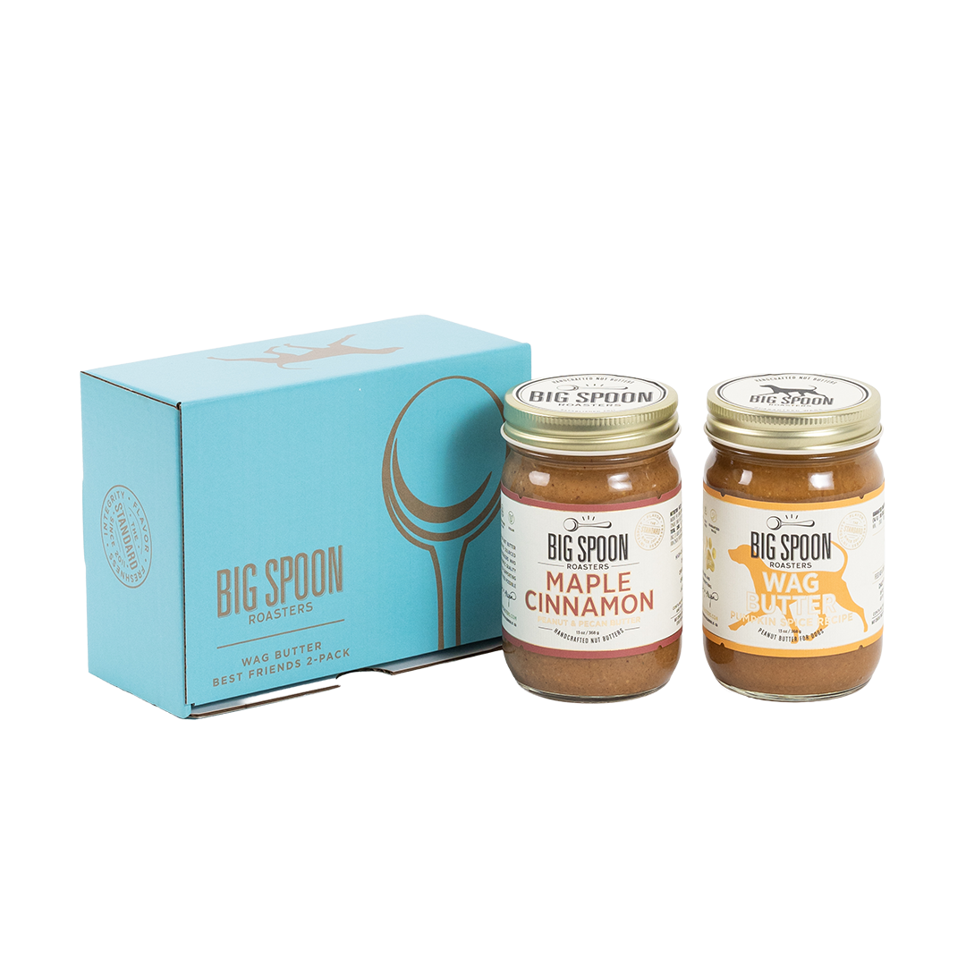 Two jars of Big Spoon Roasters nut butter in front of a closed blue gift box