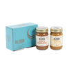 Two jars of Big Spoon Roasters nut butter in front of a closed blue gift box
