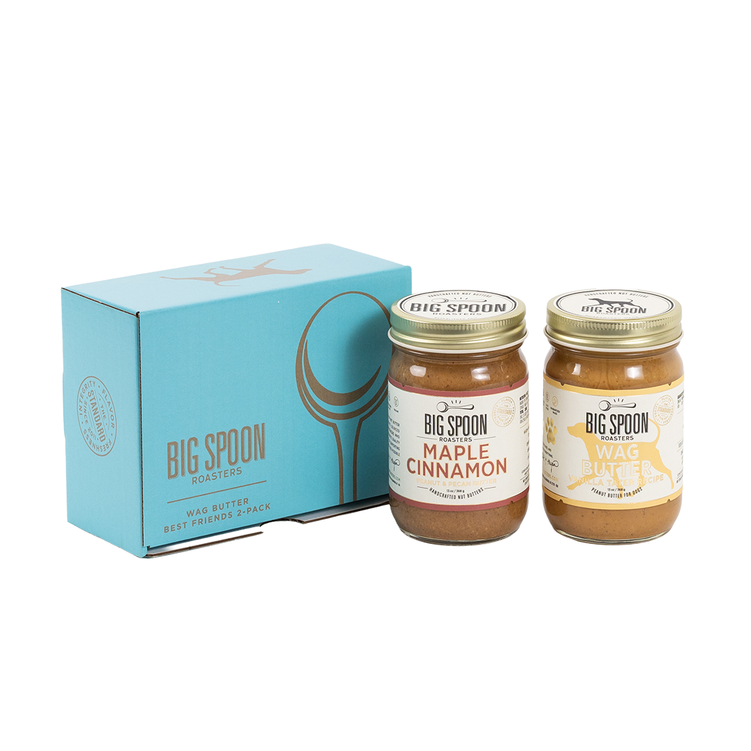 Two jars of Big Spoon Roasters nut butter in front of a closed blue gift box