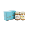 Two jars of Big Spoon Roasters nut butter in front of a closed blue gift box