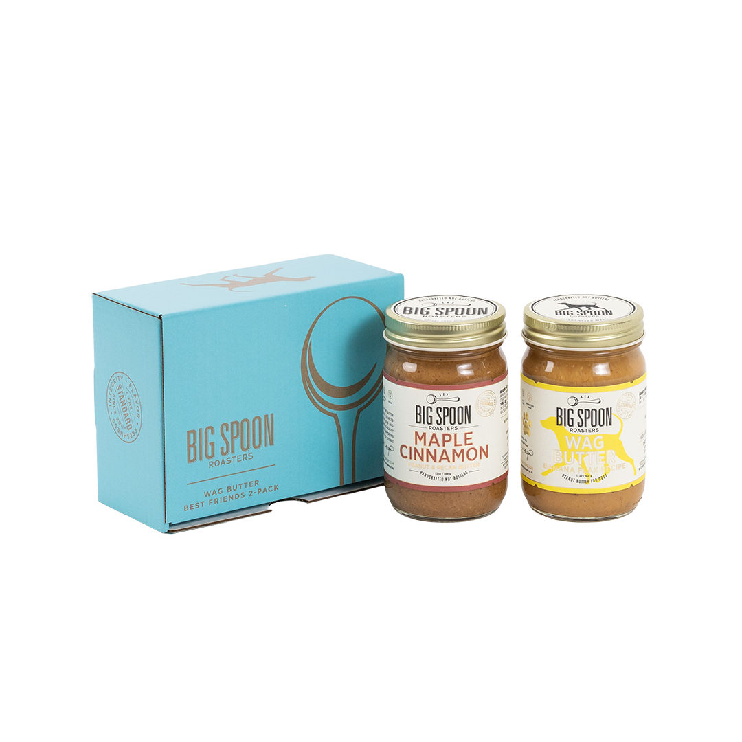 Two jars of Big Spoon Roasters nut butter in front of a closed blue gift box