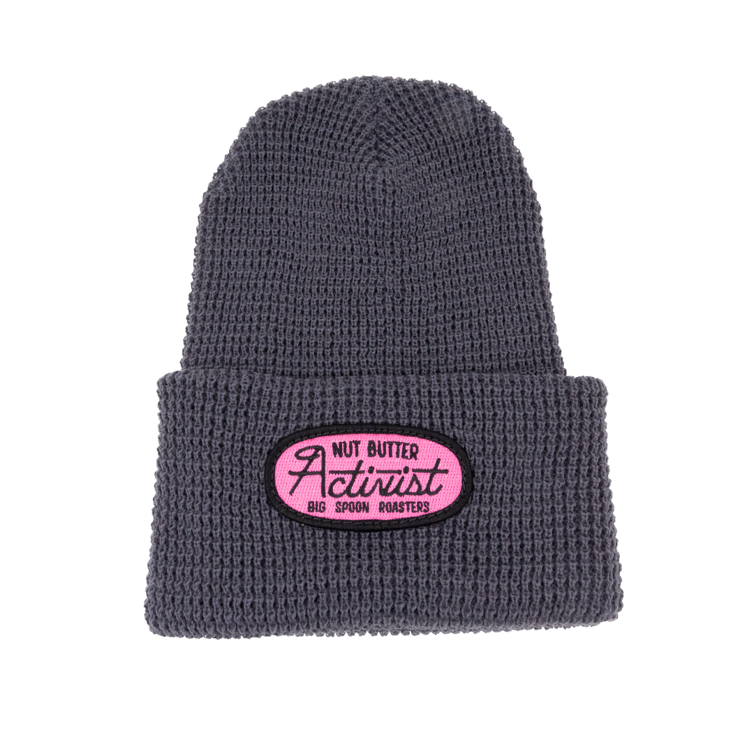 Gray beanie with a pink patch embroidered with the words NUT BUTTER ACTIVIST | BIG SPOON ROASTERS